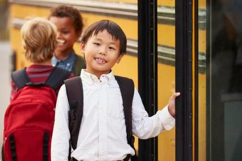 Elementary school boy at the front of the school bus queue Stock Photos