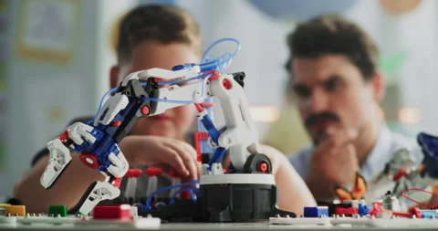 Elementary School Boy Studying Model of Innovative Robotic Arm. Teacher Helping Stock Footage 314773837