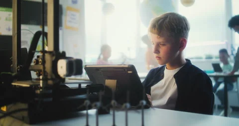 Elementary School Boy Writing Code for Advanced 3D Printer on Tablet Computer Stock Footage 311673703