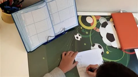Elementary school child doing homework. The boy does his homework at his desk at Stock Photos