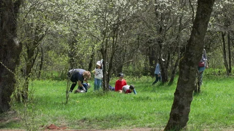Elementary school children play with their teachers at an outdoor park Stock Footage 191915059