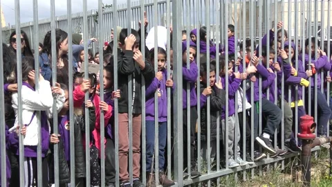 Elementary school children in yard behind fence during rocket attack drill 스톡 동영상 135361186