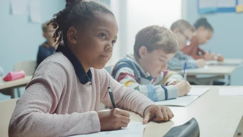 In Elementary School Classroom Brilliant Black Girl Writes in Exercise Notebook Stock-Footage 119443213