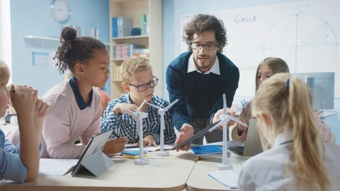 Elementary School Classroom: Teacher Holding Tablet Computer Explaining Stock Footage 119445522