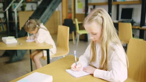 An elementary school girl is doing classwork in her notebook and asking her Stock Footage 279519017