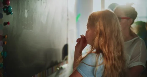 Elementary School Girl Solving Mathematical Problems on the Chalkboard with Stock Footage 313738997