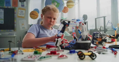 Elementary School Girl Studying Model of Innovative Robotic Arm. Teacher Helping Stock Footage 314776658