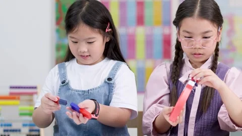 Elementary school girls exploring colorful magnet science activity together Stock Footage 329608710