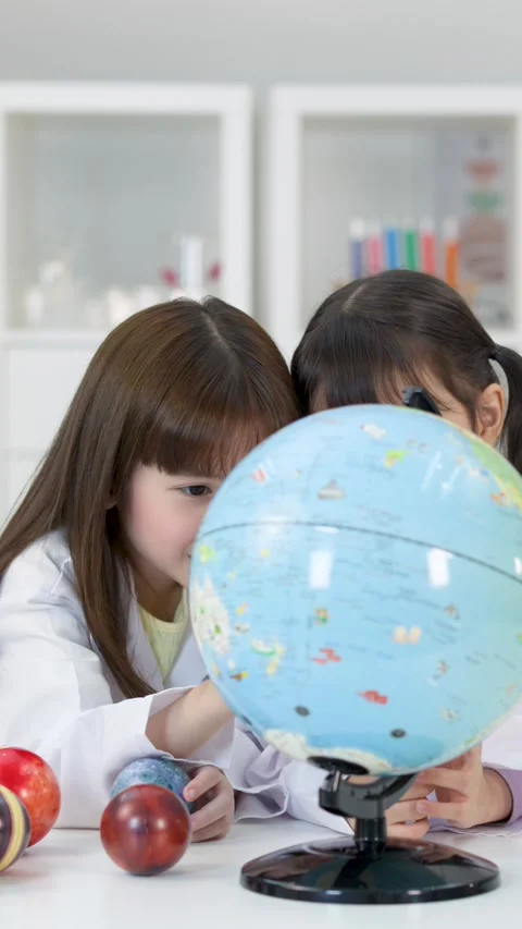 Elementary School Girls in Lab Coats Studying World Globe in Science Classroom Stock Footage 340244325
