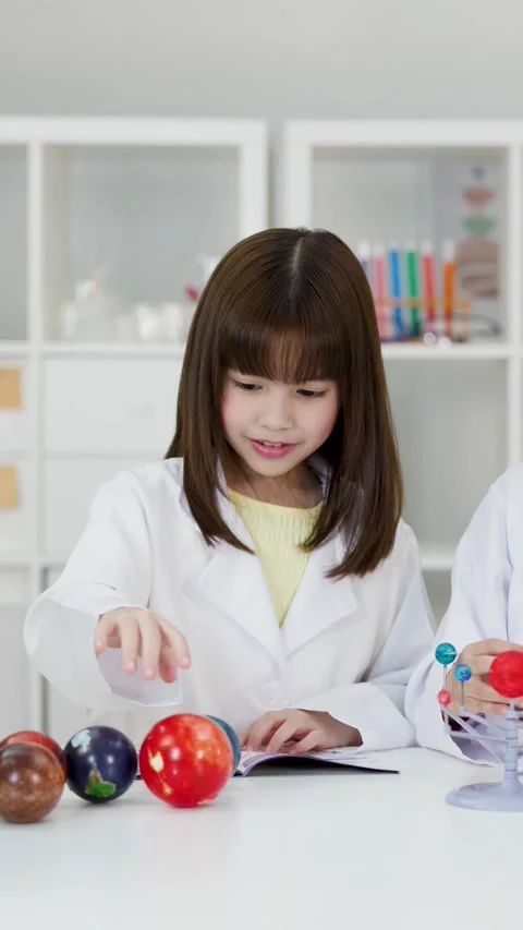 Elementary School Girls in Lab Coats Studying Solar System Model Stock Footage 341667680