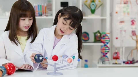 Elementary School Girls in Lab Coats Studying Solar System Model Stock Footage 341667880