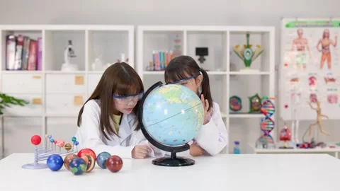 Elementary School Girls in Lab Coats Studying World Globe in Science Classroom Stock Footage 341917238