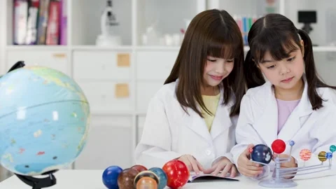 Elementary School Girls in Lab Coats Studying Solar System Model Stock Footage 342087416