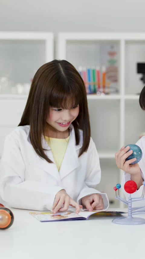 Elementary School Girls in Lab Coats Studying Solar System Model Stock Footage 344942335