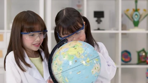 Elementary School Girls in Lab Coats Studying a World Globe Stock Footage 345194003