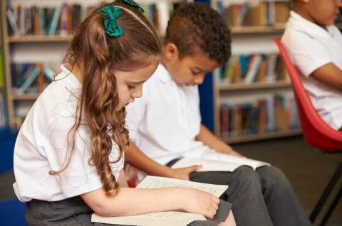 Elementary School Pupils Reading In Library Stock Photos