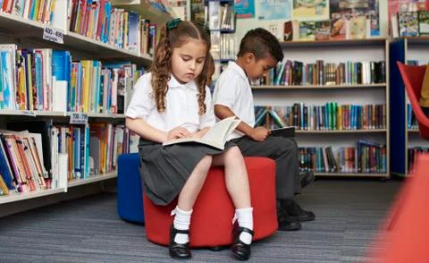 Elementary School Pupils Reading In Library Stock Photos