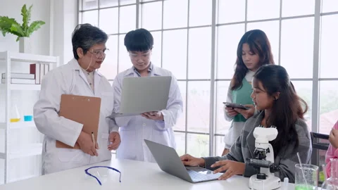 In elementary school science classroom, elderly teacher is guiding young Stock Footage 255300389