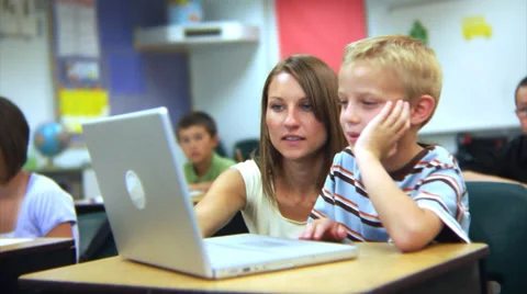 Elementary school student and teacher look at computer Stock Footage