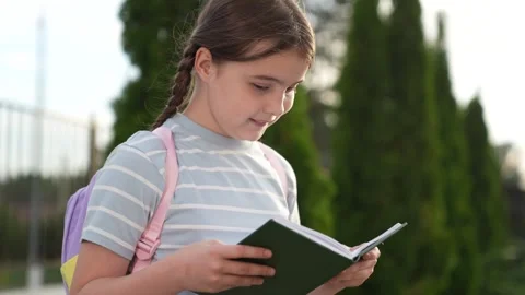 Elementary school student, child goes to class holding book hand, educational Stock Footage 315468754