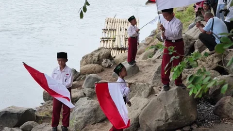 Elementary school student in uniform proudly waving the Indonesian flag during Stock Footage 346296570