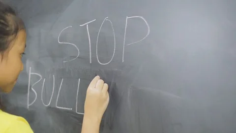 Elementary school student writes stop bullying text Stock Footage 123974896