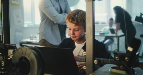 Elementary School Student Writing Code for Advanced 3D Printer on Laptop During Video stock 311675563