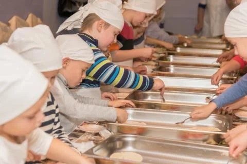 Elementary school students cook pizza during cooking class Stock Photos