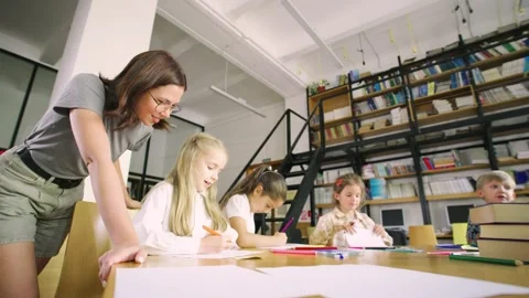 Elementary school students sit at a round table in an art class, and a young Stock Footage 279518551