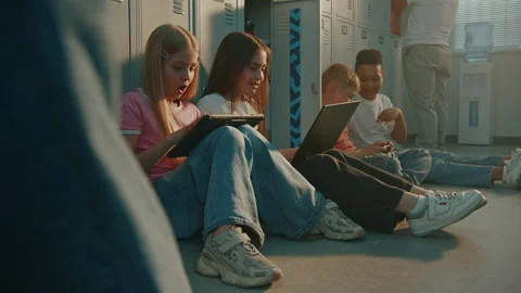 Elementary School Students Sitting on Floor in School hallway near Grey Lockers Stock Footage 342030088