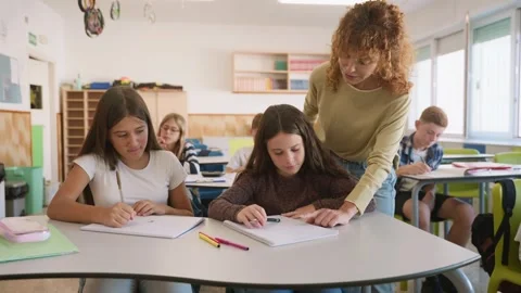 Elementary school teacher helping student in classroom Stock Footage 345113588