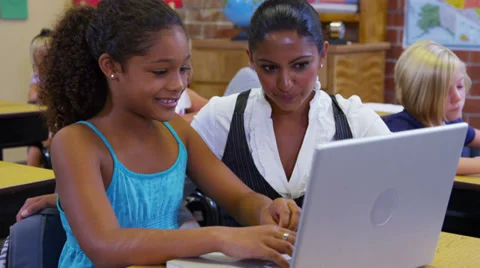 Elementary school teacher helps student with computer Stock Footage 32728526