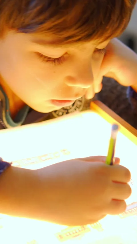 Elementary schoolboy tracing on a montessori light box vertical video Stock Footage 270796675