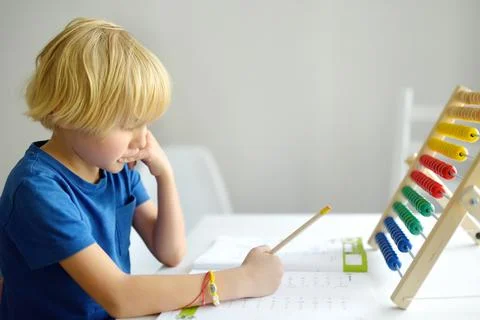 Elementary student boy doing homework at home. Child learning to count Stock Photos
