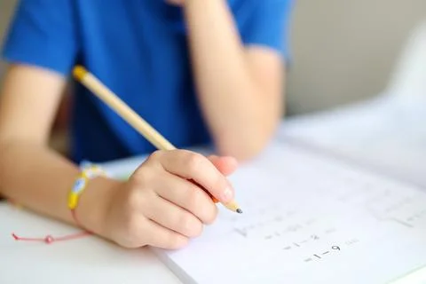 Elementary student boy doing homework at home. Child learning to count Stock Photos