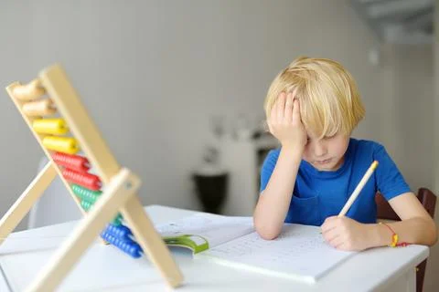Elementary student boy doing homework at home. Child learning to count Stock Photos