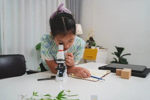 Elementary student practicing science skills using microscope during hands on Stockfoto's
