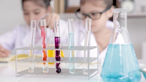 Elementary student wearing lab coat learning chemistry in school laboratory.. Stock Footage 243475204