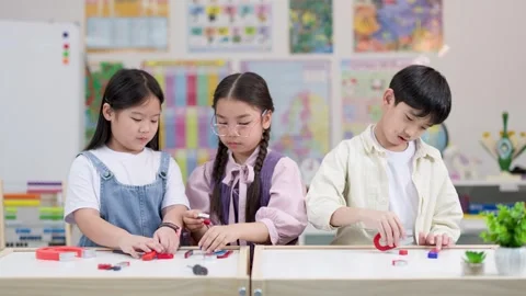 Elementary students exploring magnets in bright science classroom Stock Footage 326083690