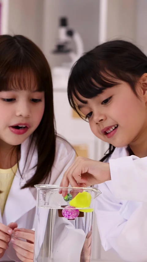 Elementary Students in Lab Coats Conducting Science Experiment with Beaker Stock Footage 346198861