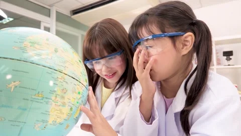 Elementary Students in Lab Coats Examining World Globe in Science Classroom Stock Footage 340183194