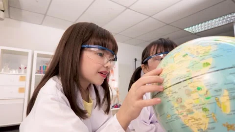 Elementary Students in Lab Coats Studying World Globe in Science Classroom Stock Footage 340244425