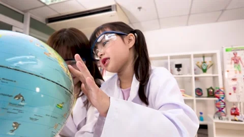 Elementary Students in Lab Coats Studying World Globe in Science Classroom Stock Footage 340775384