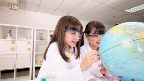 Elementary Students in Lab Coats Studying World Globe in Science Classroom Stock Footage 341319642