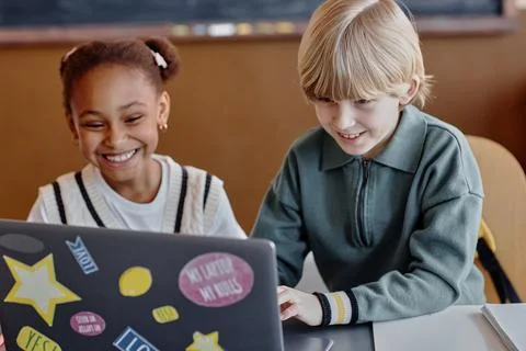 Elementary Students Working Together on Computer in Classroom Foto stock
