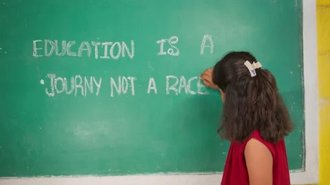Elementry Girl kid looking at camera after writing education quote on chalkboard Stock Footage 200896057