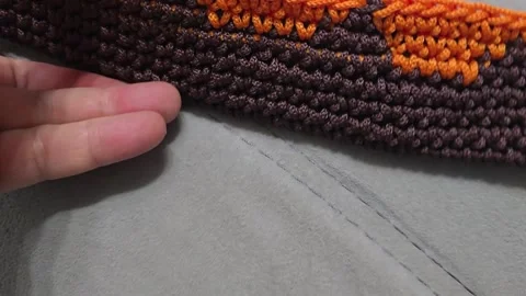 Elements of a bag crocheted from brown and orange cord. On a wooden base. Stock Footage 313859299