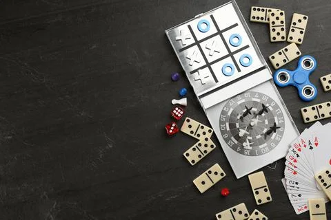 Elements of different board games on black slate table, flat lay. Space for t Stock Photos