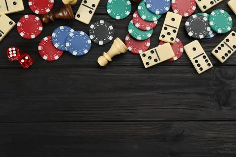 Elements of different board games on dark wooden table, flat lay. Space for t 库存照片