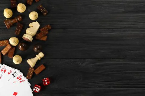 Elements of different board games on dark wooden table, flat lay. Space for t 库存照片